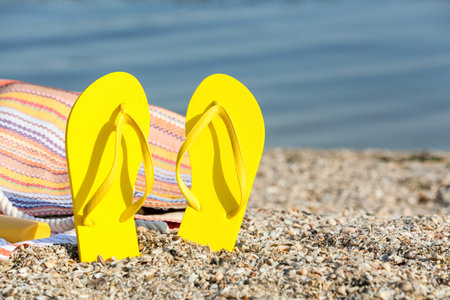 Stylish flip-flops and bag on sea beachの写真素材