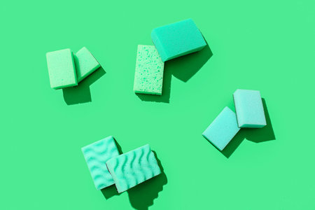 Green cleaning sponges on color background