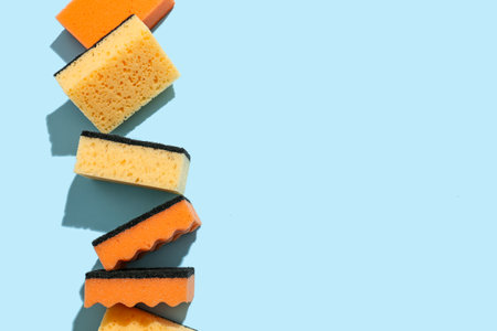 Orange cleaning sponges on color background