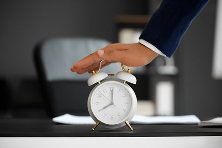 Young businessman with white alarm clock at table in office, closeupの写真素材