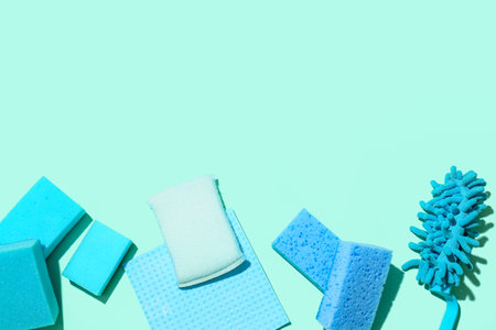 Different cleaning sponges and rag on color background