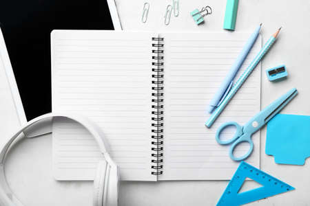 Blank notebook, gadgets and stationery on light grunge background