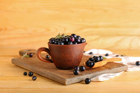 Cup and scoop with ripe black currant on wooden backgroundの写真素材
