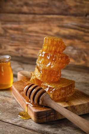 Board with honey combs and dipper on wooden backgroundの写真素材