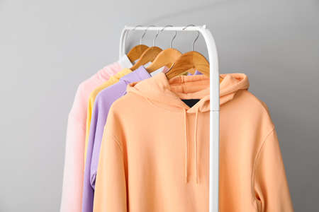 Rack with stylish hoodies near light wallの写真素材