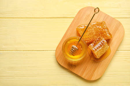 Bowl of honey and combs on yellow wooden backgroundの写真素材