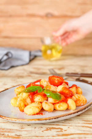 Delicious gnocchi with tomato sauce in plate on wooden tableの写真素材