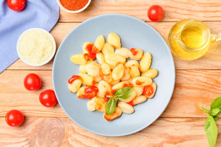 Delicious gnocchi with tomato sauce in plate on wooden backgroundの写真素材
