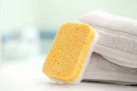 Bath sponge and towels on table in bathroom, closeup