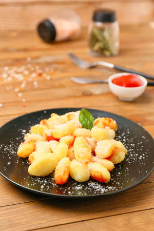 Delicious gnocchi with tomato sauce in plate on wooden tableの写真素材