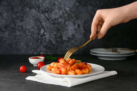 Woman eating delicious gnocchi with tomato sauce on dark backgroundの写真素材