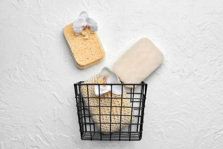 Basket with bath sponges and flowers on light backgroundの写真素材