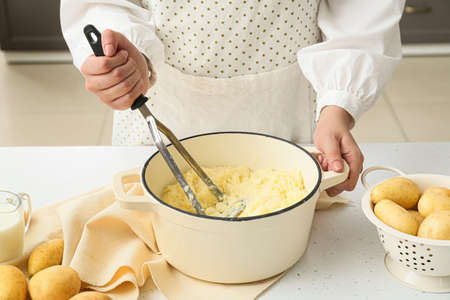 Woman preparing tasty mashed potatoes on table in kitchen, closeupの写真素材
