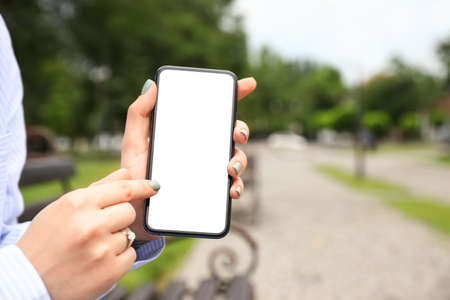 Young woman pointing on blank mobile phone screen outdoors, closeup