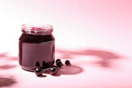 Jar with black currant jam on color backgroundの写真素材