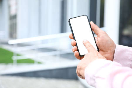 Man typing on mobile phone with blank screen on city street, closeup