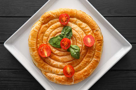 Plate with tasty spinach pie on dark wooden background
