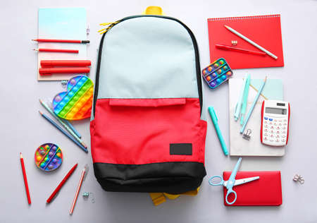 School backpack and stationery on light background