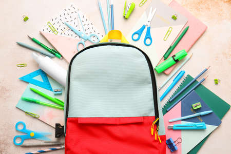 School backpack and stationery on light background