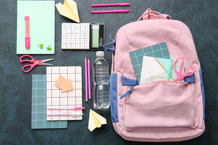 School backpack and stationery on dark background
