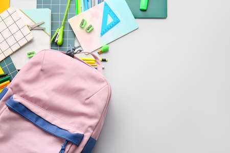 School backpack and stationery on light background