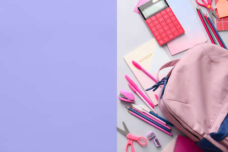 School backpack and stationery on color background