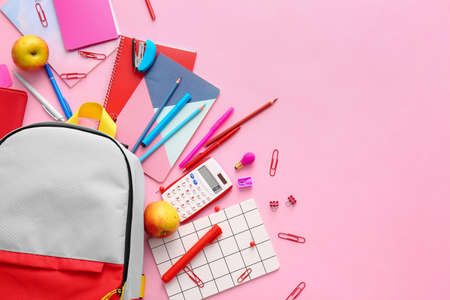 School backpack and stationery on color background