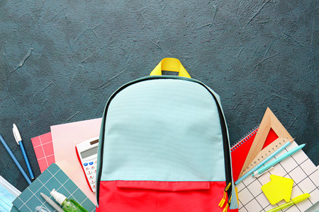 School backpack and stationery on dark background