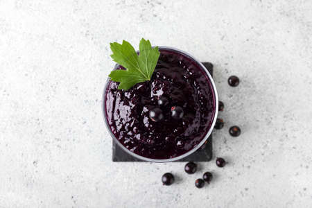 Bowl with delicious black currant jam on light backgroundの写真素材