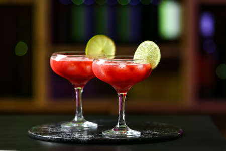 Glasses of tasty strawberry margarita on table in barの写真素材