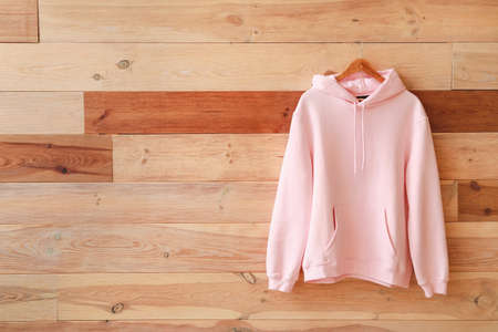 Modern hoodie hanging on wooden wall