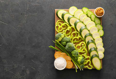 Wooden board with different green vegetables on dark backgroundの写真素材