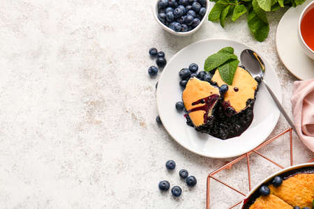 Plate with pieces of blueberry cobbler on light backgroundの写真素材