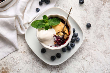 Ramekin with blueberry cobbler and ice cream on light backgroundの写真素材