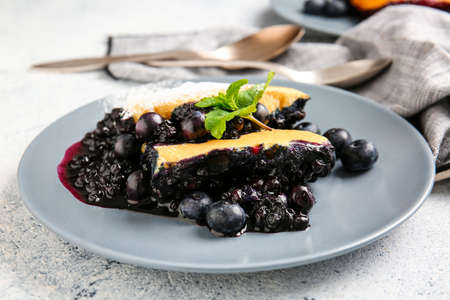 Plate with pieces of blueberry cobbler on light background, closeupの写真素材