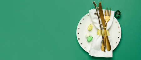 Stylish Easter table setting on green background with space for textの写真素材