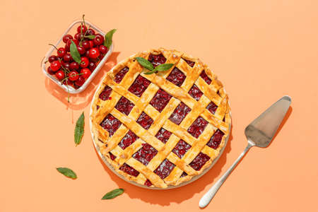 Plate with tasty cherry pie and spatula on color backgroundの写真素材