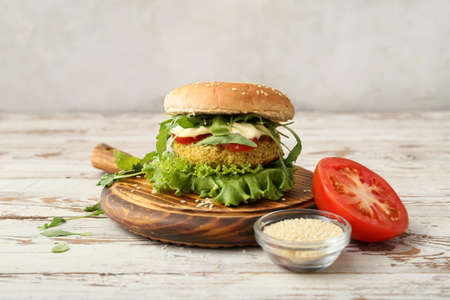 Wooden board with tasty vegetarian burger on tableの写真素材