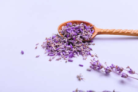 Spoon with lavender flowers on color background