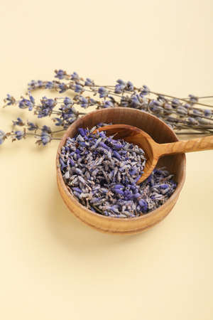 Bowl and spoon with lavender flowers on color background