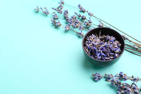 Bowl with lavender flowers on color background