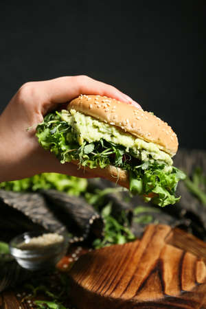 Woman holding tasty vegetarian burger on black backgroundの写真素材