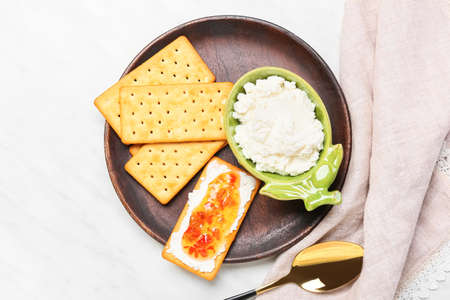 Delicious breakfast with crackers and jalapeno pepper jam on light background