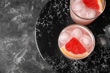 Glasses of tasty grapefruit margarita on grunge background, closeupの写真素材