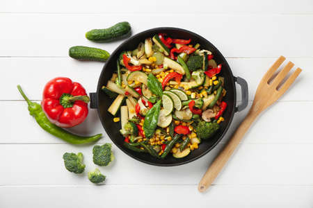 Frying pan with different vegetables on light wooden backgroundの写真素材