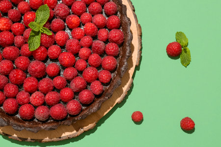 Board with tasty raspberry pie and mint on color background