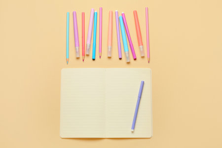 Colorful markers, pencils and blank notebook on color backgroundの写真素材