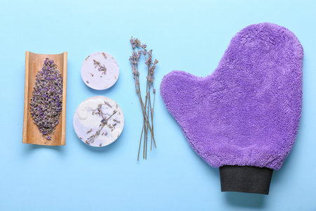 Soap bars, massage glove and lavender flowers on color backgroundの写真素材