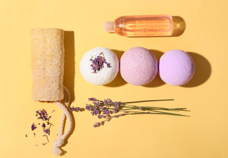 Composition with bath bombs, sponge, bottle of cosmetic product and lavender flowers on color backgroundの写真素材