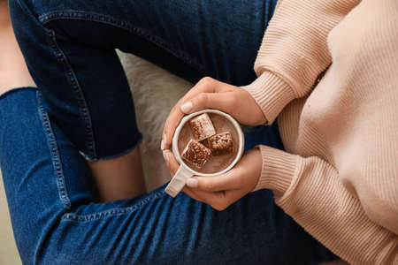 Woman sitting and holding cup of delicious cacao, closeup